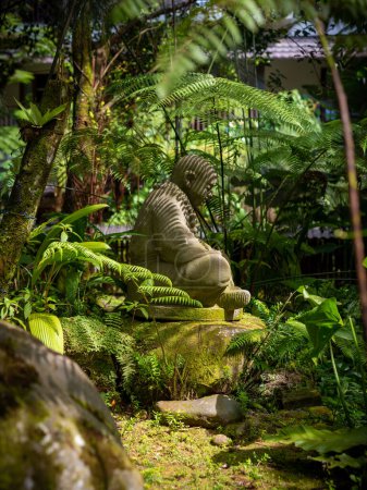 Foto de One small stone buddha statue with lush tropical vegetation surrounding it, Berastagi, Indonesia. Taken on a sunny day with no people. - Imagen libre de derechos