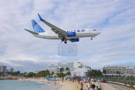 Téléchargez les photos : United Airlines Boeing 737 survolant Maho Beach avant d'atterrir sur l'aéroport international Princess Juliana SXM à Sint Maarten, aux Pays-Bas Caraïbes. - en image libre de droit