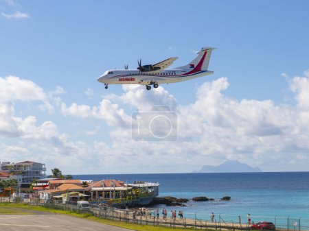 Téléchargez les photos : Winair (Windward Islands Airways) ATR 42 survolant Maho Beach avant d'atterrir sur l'aéroport international Princess Juliana SXM à Sint Maarten, dans les Caraïbes néerlandaises. - en image libre de droit