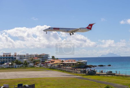 Téléchargez les photos : One Caribbean Sunrise Airways Embraer ERJ-145LR survolant Maho Beach avant d'atterrir sur l'aéroport international Princess Juliana SXM à Sint Maarten, Pays-Bas Caraïbes. - en image libre de droit