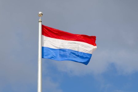 Photo for Flag of the Kingdom of the Netherlands flying on a cloudy sky on Saba, Caribbean Netherlands. - Royalty Free Image