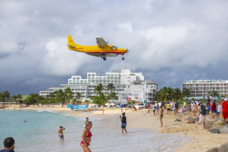 Téléchargez les photos : DHL Cessna 208B Super Cargomaster survolant Maho Beach avant d'atterrir sur l'aéroport international Princess Juliana SXM au coucher du soleil sur Sint Maarten, aux Caraïbes néerlandaises. - en image libre de droit