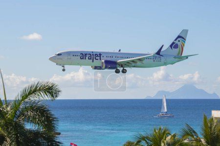 Téléchargez les photos : Arajet Boeing 737 Max 8 survolant Maho Beach avant d'atterrir sur l'aéroport international Princess Juliana SXM à Sint Maarten, Pays-Bas Caraïbes. - en image libre de droit