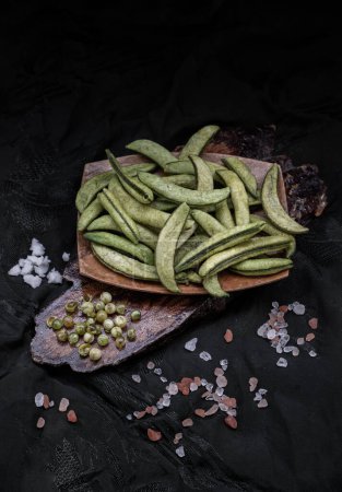Photo for Healthy roasted sugar snap peas on dark wooden background. Home cooking, Dark tone, Space for text, Selective Focus. - Royalty Free Image