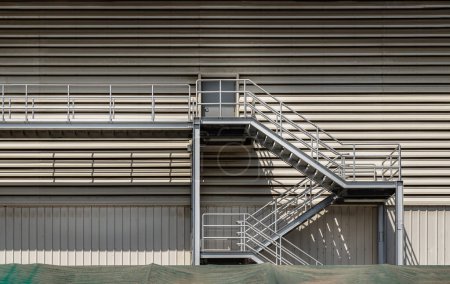 Foto de Bangkok, Tailandia - 12 de diciembre de 2022: Vista lateral de una escalera de metal externa como ruta de escape de incendios en un moderno edificio de almacén. Elementos arquitectónicos interesantes, Concepto de salida de emergencia, Enfoque selectivo. - Imagen libre de derechos