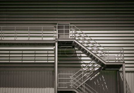 Foto de Bangkok, Tailandia - 12 de diciembre de 2022: Vista lateral de una escalera de metal externa como ruta de escape de incendios en un moderno edificio de almacén. Elementos arquitectónicos interesantes, Concepto de salida de emergencia, Enfoque selectivo. - Imagen libre de derechos