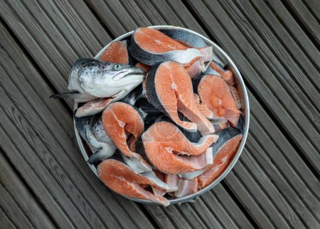Photo for Metal baking tray filled with Large pieces of fresh raw atlantic salmon and Fresh salmon head. The protein is cut into steaks exposing the bright orange color of the fish with grey and black skin. Preparation nutrition seafish, The concept of healthy - Royalty Free Image
