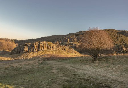 Téléchargez les photos : Le paysage pittoresque à couper le souffle du parc Holyrood avec les collines escarpées de Salisbury Crags et le fond du ciel. Vue de la ville d'Édimbourg. Espace pour le texte, Mise au point sélective. - en image libre de droit