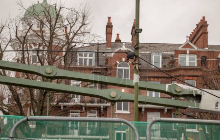 London, UK - Dec 25, 2023 - Structure of Hammersmith Bridge with old building background. One of the world's oldest suspension bridge and a major river crossing and primary route in west london, Space for text, Selective focus.