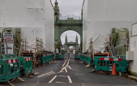 Photo for London, UK - Dec 25, 2023 - Hammersmith Bridge closed for while undergoing a complete refurbishment and repairing. One of the world oldest suspension bridges and a major river crossing and primary route in west london, The approach to a heavily - Royalty Free Image