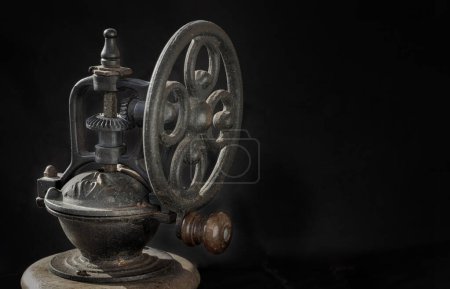 Detail of Antique coffee bean original grinder metal shake wheel with hand crank on dark background. Close-up of Old original coffee grinder, Space for text, Selective focus.