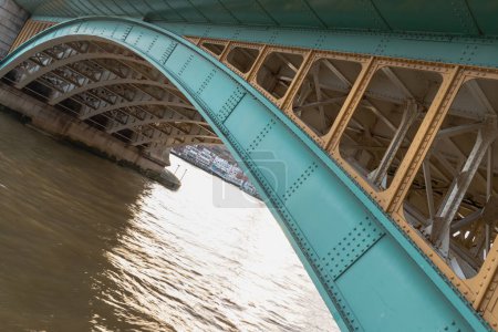 London, UK - Feb 27, 2024 - Detail of Structure and Girders supporting Southwark Bridge Over The River Thames in London. The side of a turquoise cast iron bridge, Curved steel Bridge, Space for text, Selective focus.