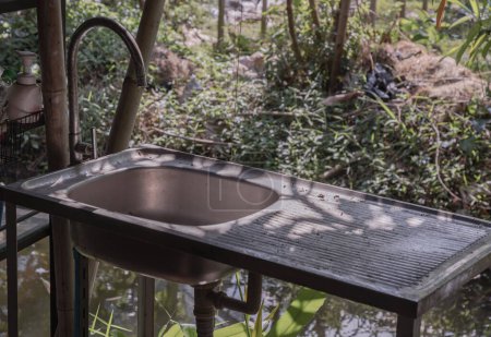 Wasserhähne über Edelstahlspüle zum Händewaschen außerhalb des Hauses am Kanal. Altes Waschtisch-Waschtisch-Set aus Edelstahl, Platz für Text, Selektiver Fokus.