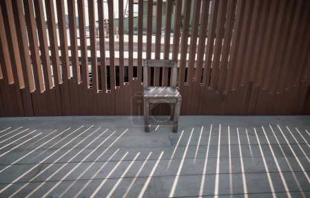 Photo for The old wooden chair is in front of the wall, which the sunlight is through it. Relaxing corner in the sunny day with good atmosphere, Space for text, Selective focus. - Royalty Free Image