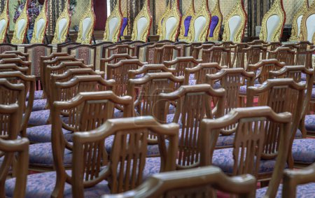 Bangkok, Thailand - May 22, 2024 - Perspective view of Wooden chairs with cushion seat and Pulpit within Samphanthawong Saram Worawihan temple. Space for text, Selective focus.