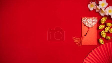 Photo for Flat lay Chinese Lunar New Year background. red envelope, Tae Eia, ang pow for giving money on Chinese new year celebrate with ancient Chinese gold bar, plum blossom, paper fan for ornament copy space - Royalty Free Image
