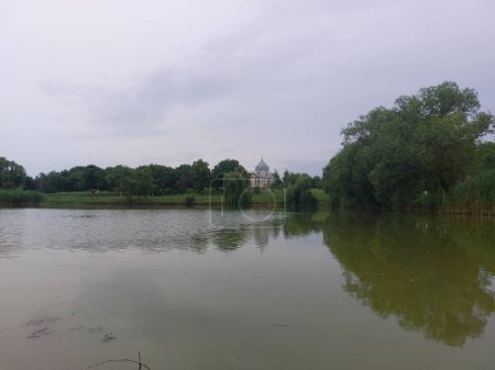 Ein kleiner See mit Weiden am Ufer. Kirche am See. Entspannung am Wasser. Altes Boot an malerischem Ort