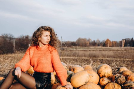 Photo for Against the background of autumn park smiles beautiful smile curly brunette. young curly girl in an orange sweater against the backdrop of autumn nature - Royalty Free Image
