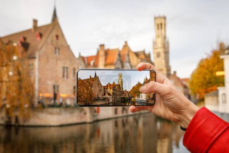 Traveling old Europe. Taking the picture of Brugge iconic view via smartphone