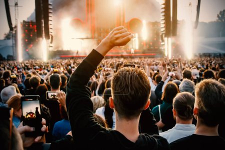 People with raised hands enjoy music concert
