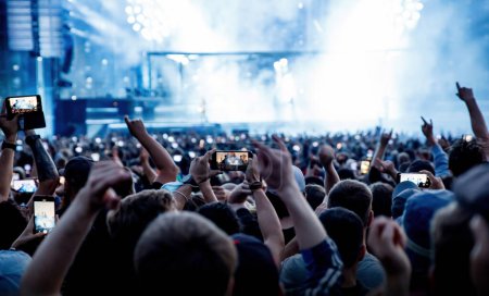 Téléchargez les photos : The happy crowd in a concert hall. Silhouettes of raised hands - en image libre de droit