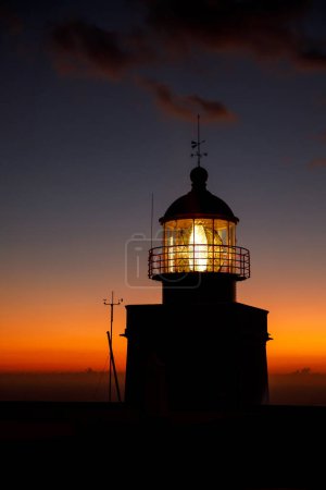 Photo for The classic lighthouse silhouette during the sunset, dramatic clouds in the sky - Royalty Free Image