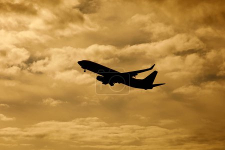 Téléchargez les photos : Décollage de l'avion dans les nuages orange coucher de soleil fond - en image libre de droit