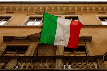 Bandera italiana en el antiguo balcón del edificio en el casco antiguo. Vista inferior