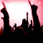 Girl on shoulders silhouette. Happy people with raised hands at a music concert