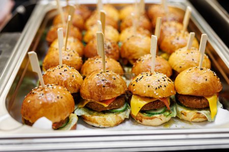 Photo for Mini burgers with sesame seeds on a metal tray. - Royalty Free Image