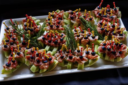 Photo for A platter of appetizing hors d oeuvres with colorful skewers on a black background - Royalty Free Image