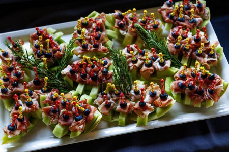Photo for A platter of appetizing hors d oeuvres with colorful skewers on a black background - Royalty Free Image