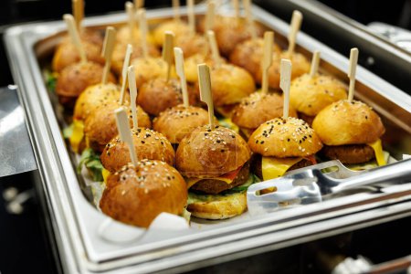 Photo for A platter of savory mini burgers with toothpicks and condiments. - Royalty Free Image