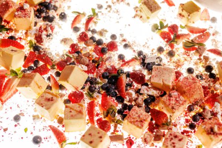 Téléchargez les photos : Un tableau de desserts coloré et vibrant avec des bouchées de fruits frais et de cheesecake, saupoudré de sucre en poudre pour un régal sucré et indulgent - en image libre de droit