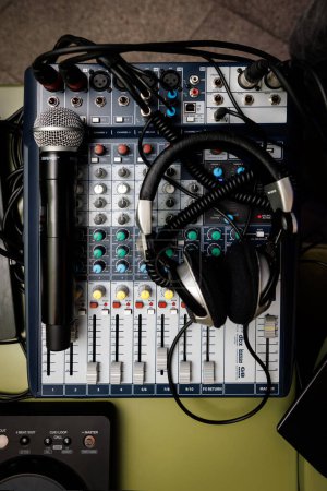 Téléchargez les photos : Console de mixage audio professionnelle avec microphone et écouteurs, présentant une configuration prête à l'emploi pour l'ingénierie du son et la production musicale. - en image libre de droit