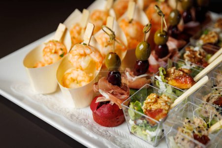 Une présentation gastronomique d'entrées assorties, avec de succulentes crevettes et une variété de délicieuses bouchées, élégamment servies sur un plateau blanc