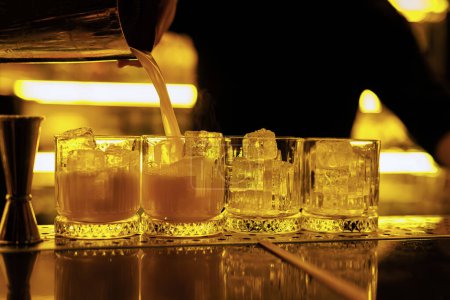 Photo for The bartender pours a whiskey sour cocktail into elegant glasses - Royalty Free Image