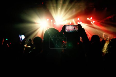 Evento de música en vivo, mostrando a un miembro del público grabando el espectacular espectáculo de luz y concierto de música