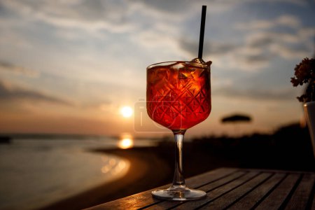 Verre de cocktail dans un restaurant de plage sur fond de coucher de soleil