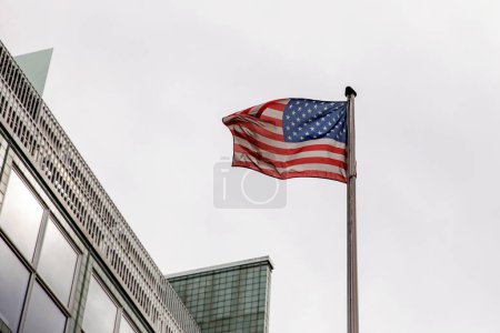 American flag gracefully waving against a backdrop of modern architectural buildings