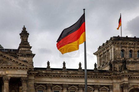 Die Deutschlandfahne weht stolz vor dem deutschen Parlamentsgebäude vor bewölktem Himmel