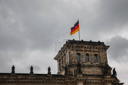 Die Deutschlandfahne weht stolz vor dem deutschen Parlamentsgebäude vor bewölktem Himmel