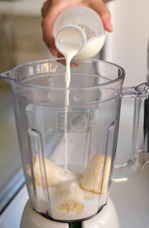 Téléchargez les photos : Femme préparant milkshake ajoutant du lait au mélangeur gros plan des mains - en image libre de droit