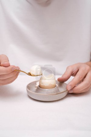 Foto de Un hombre come un huevo para desayunar en un tazón escalfado vista superior - Imagen libre de derechos