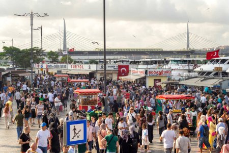 Foto de Estambul, Turquía - 30 de agosto de 2022: Multitud de ciudadanos locales en la Plaza Eminonu durante las vacaciones del Día de la Victoria con el trasfondo de la vista de la ciudad de Estambul, incluido el Puente del Metro del Cuerno de Oro - Imagen libre de derechos