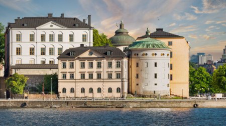 Téléchargez les photos : Une silhouette de la tour Birger Jarls, une tour du XVIe siècle, chancelière de la justice et chancelière de la justice à Stockholm, en Suède, se dresse sur la rive d'un lac calme alors que le soleil se couche sur la ville - en image libre de droit