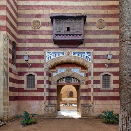 Auffällige rot-weiß gestreifte gewölbte Eingangstür führt in ein Gebäude im Stil der Mamluk-Ära, das komplexe architektonische Details präsentiert