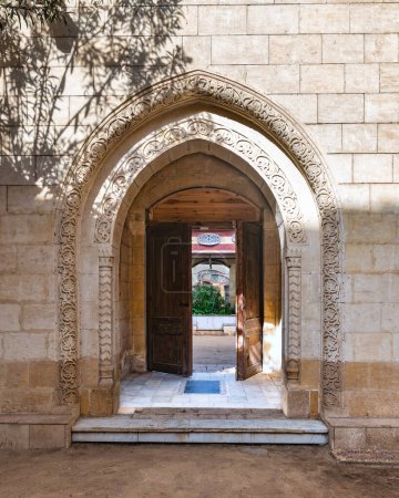 Sunlight filters through an ornate stone archway leading into a serene courtyard