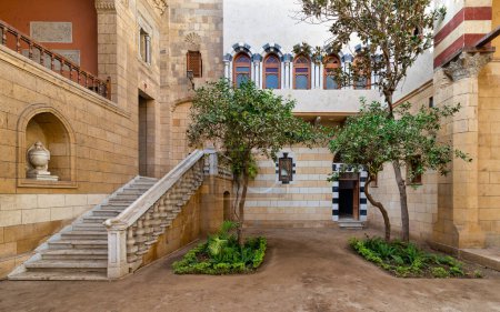 Patio del Palacio del Príncipe Naguib, El Cairo, Egipto, donde exuberante vegetación y elegante arquitectura crean un santuario tranquilo. La acogedora escalera llama a la exploración