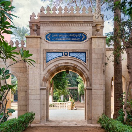 Ein kunstvoller Torbogen im mamlukischen Stil führt zu einem ruhigen Garten am Prince Naguib Place in Kairo, Ägypten, der historische Architektur präsentiert